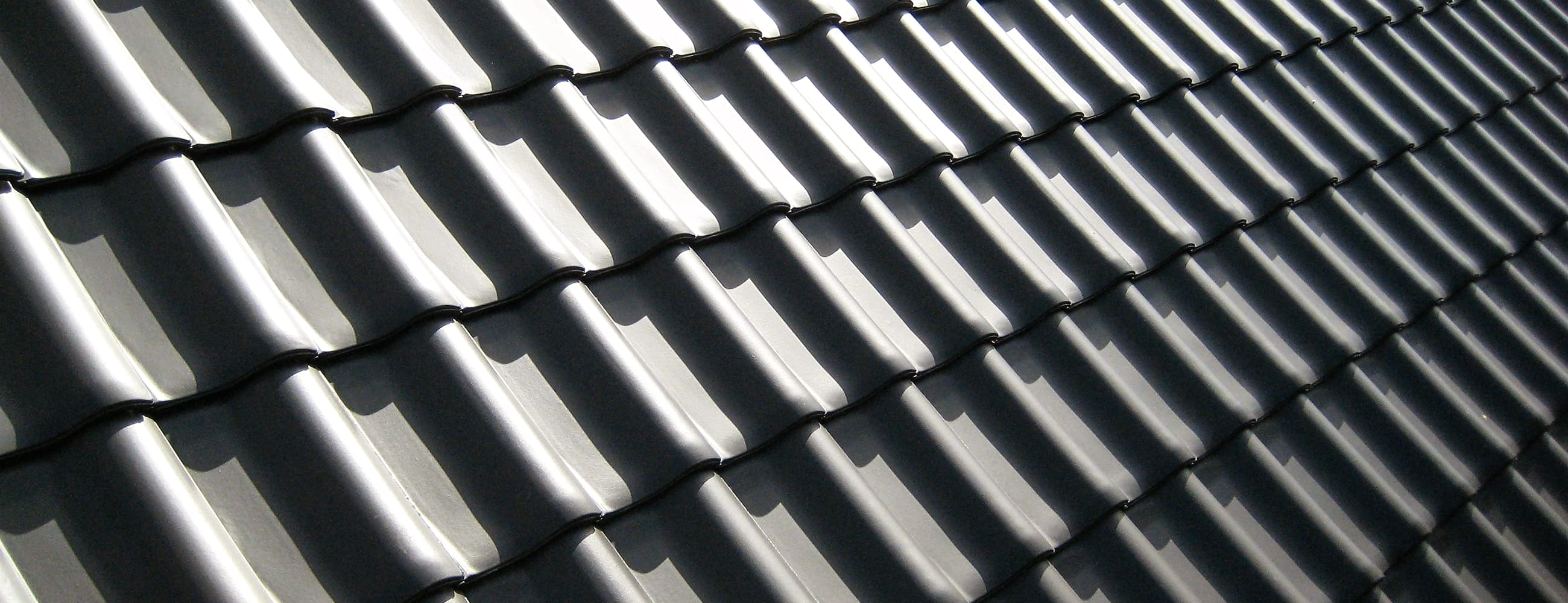 Roof tiles laid in clean rows, raking with afternoon light and shadow